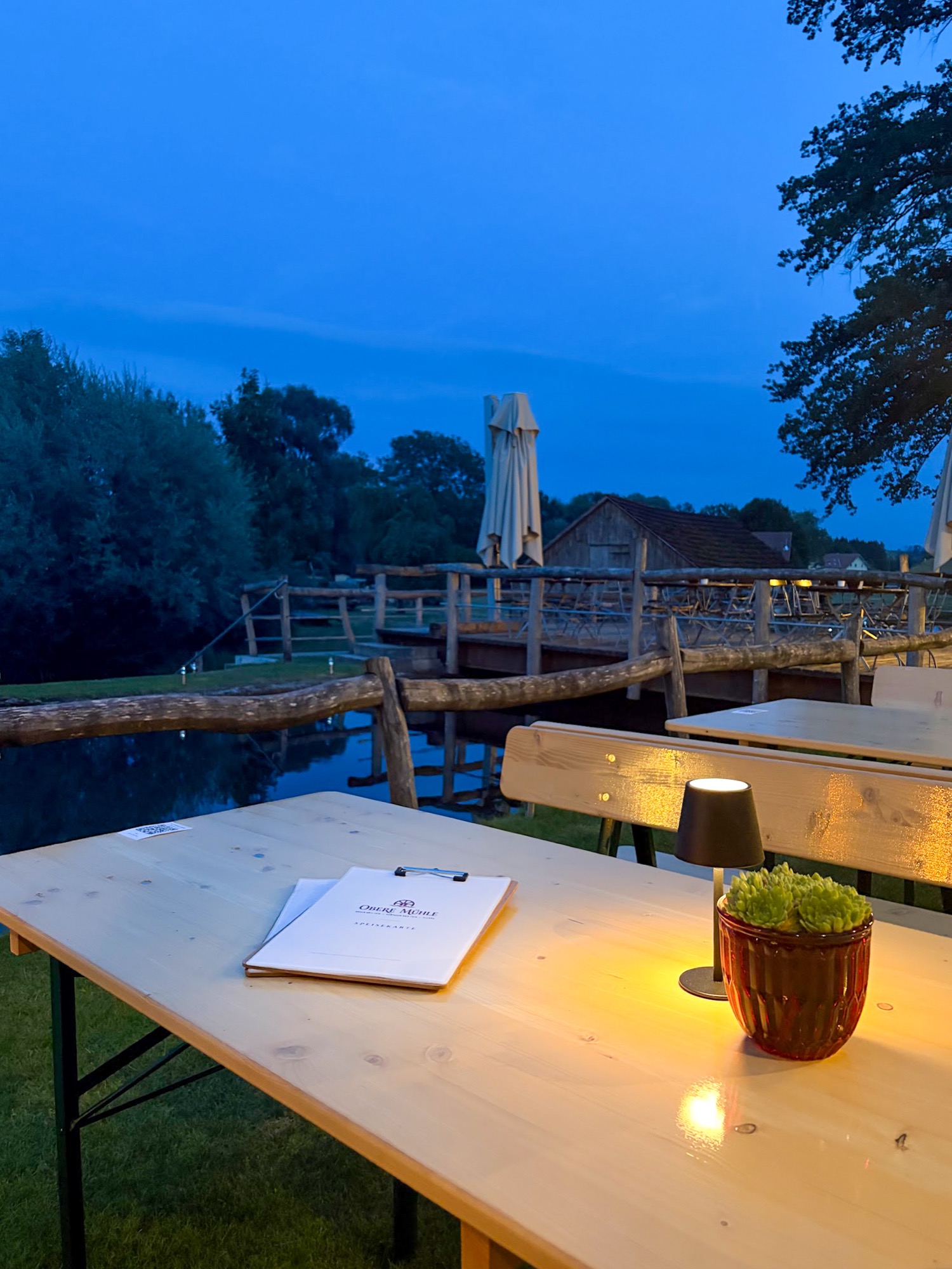 Abendstimmung im Biergarten der Oberen Mühle am Wasser, gedeckter Tisch mit Lampe