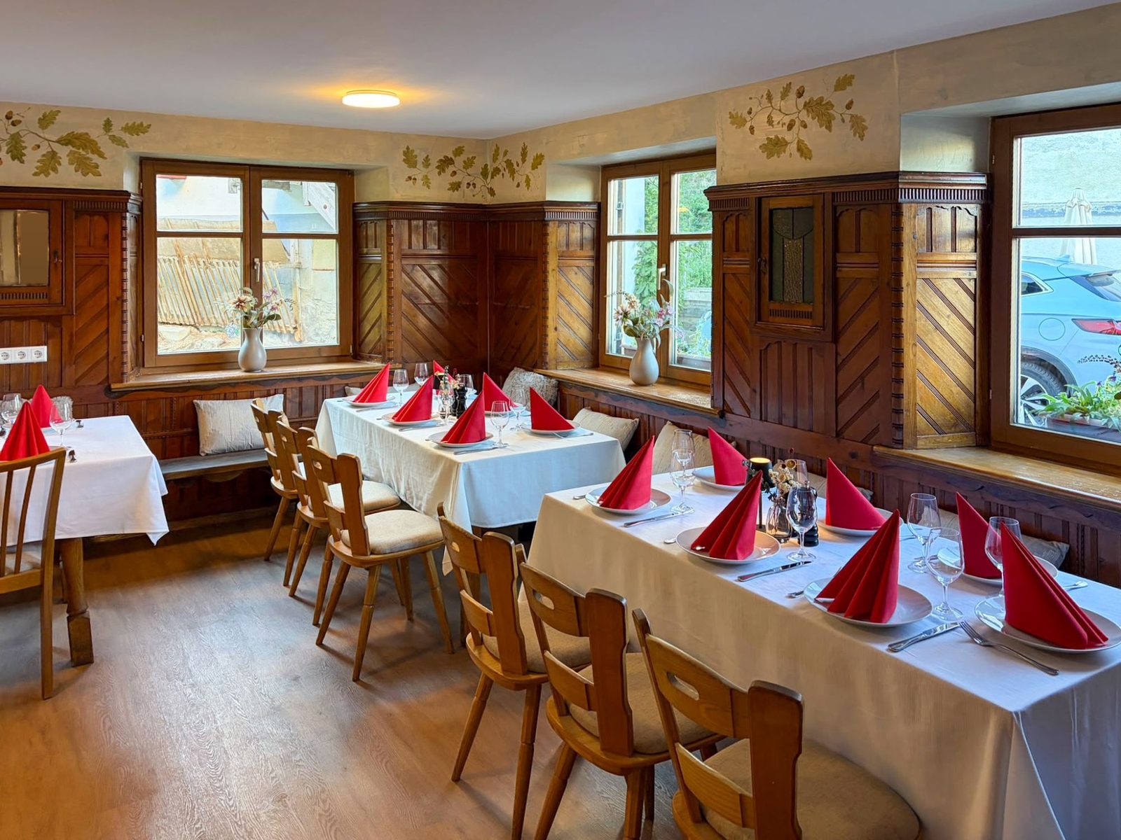 Ecke des renovierten Raums mit Holztäfelung, Eichenlaub-Malerei an der Wand und gedeckten Tischen